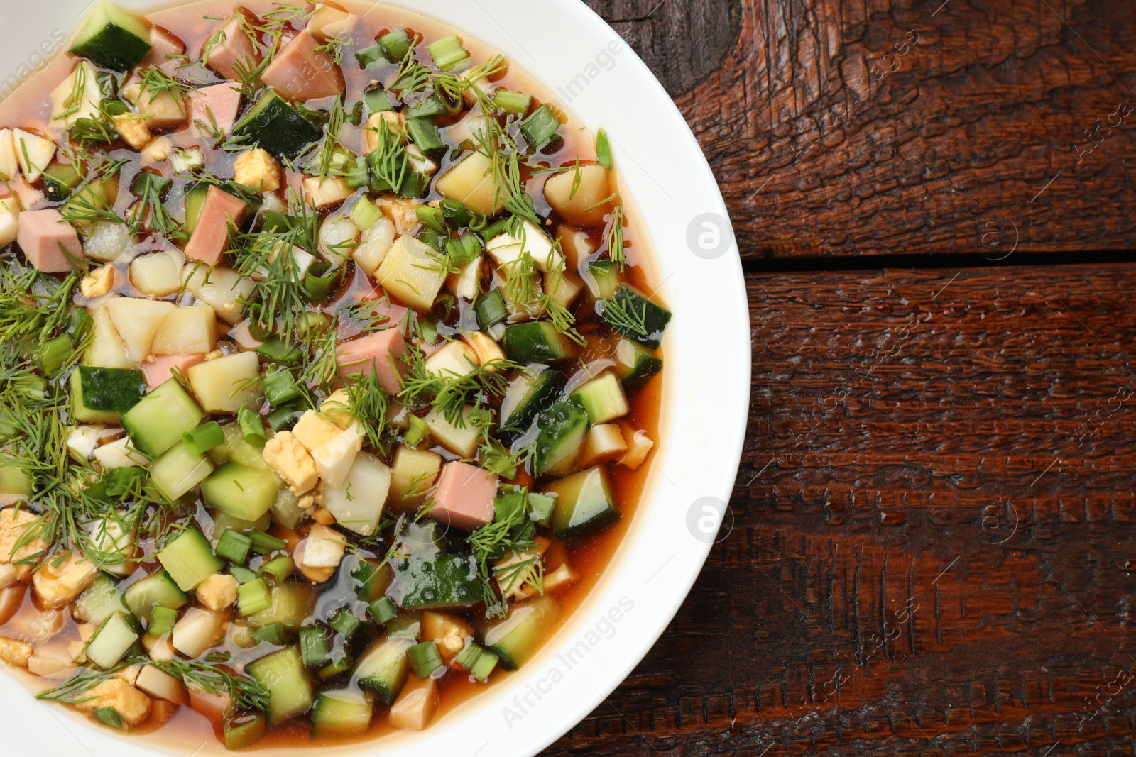 Photo of Tasty okroshka soup with kvass in bowl on wooden table, top view. Space for text