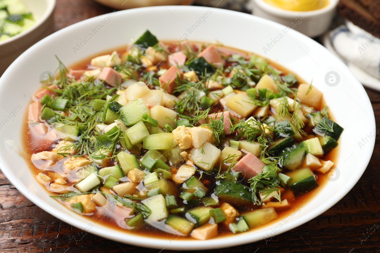 Photo of Tasty okroshka soup with kvass in bowl on wooden table, closeup