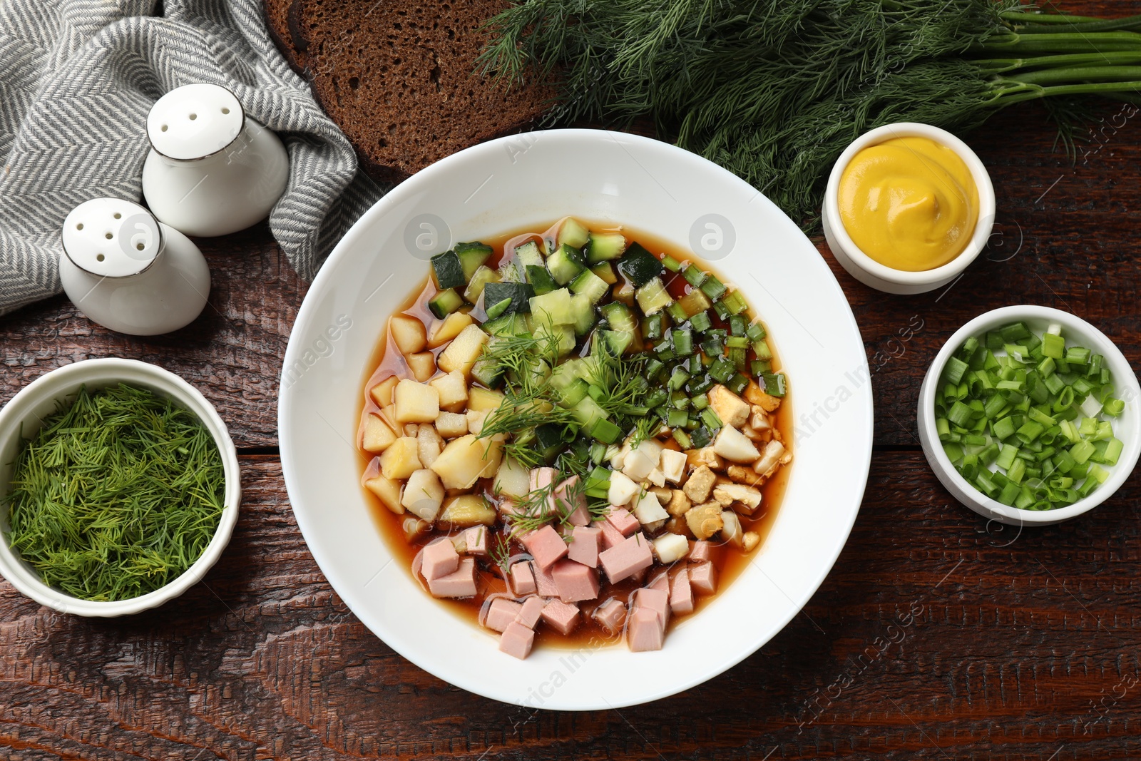 Photo of Tasty okroshka soup with kvass and ingredients on wooden table, flat lay