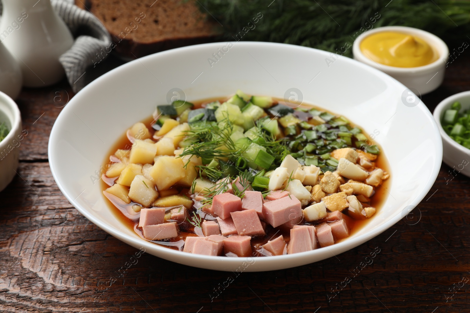 Photo of Tasty okroshka soup with kvass and ingredients on wooden table, closeup