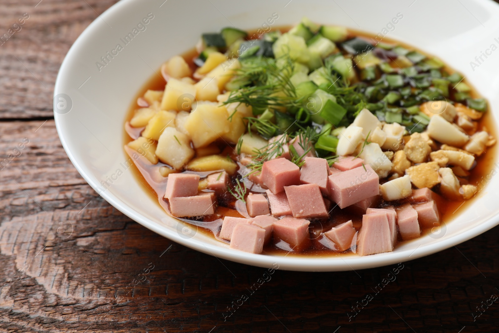 Photo of Tasty okroshka soup with kvass in bowl on wooden table, closeup