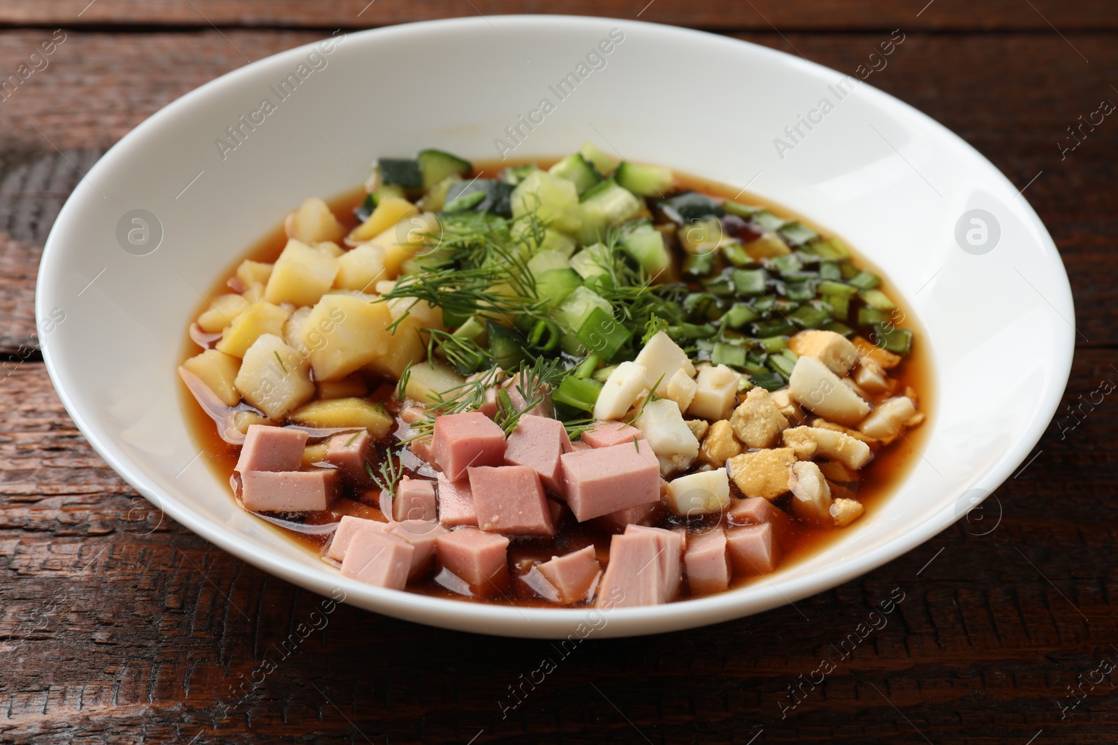 Photo of Tasty okroshka soup with kvass in bowl on wooden table, closeup