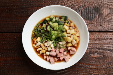 Photo of Tasty okroshka soup with kvass in bowl on wooden table, top view