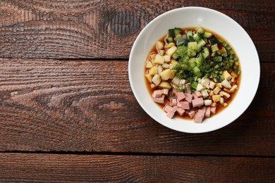 Photo of Tasty okroshka soup with kvass in bowl on wooden table, top view. Space for text