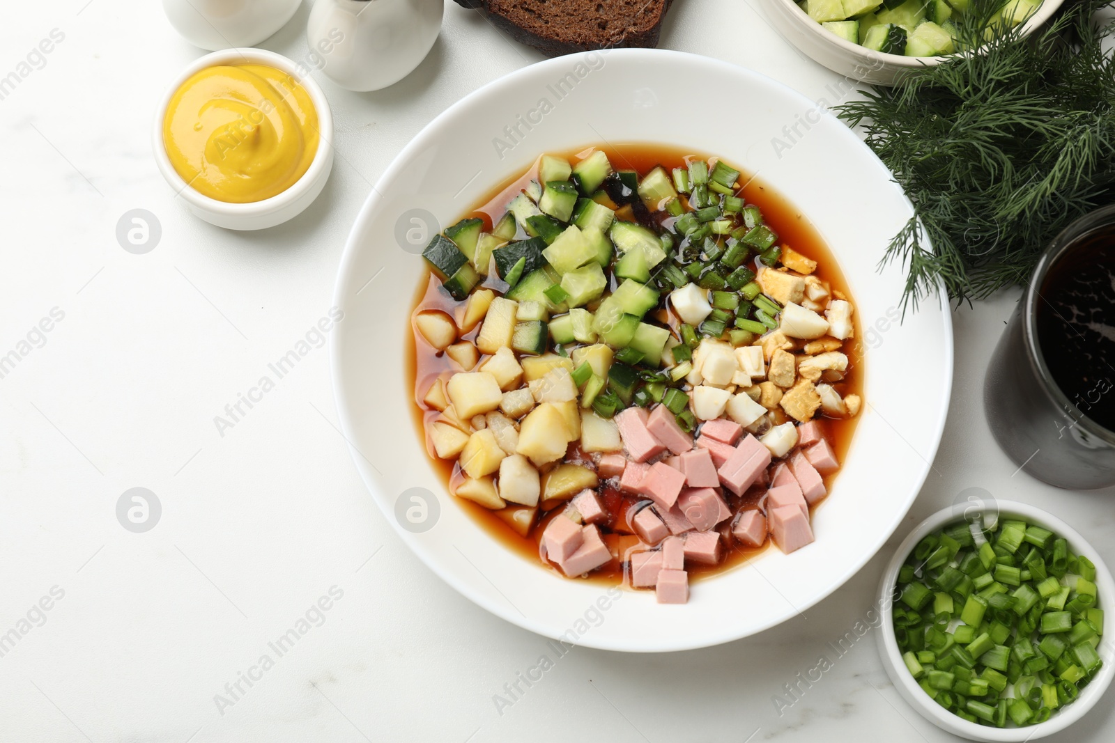 Photo of Tasty okroshka soup with kvass and ingredients on white marble table, flat lay. Space for text