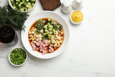 Photo of Tasty okroshka soup with kvass and ingredients on white marble table, flat lay. Space for text