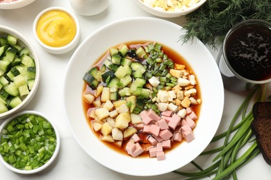 Photo of Tasty okroshka soup with kvass and ingredients on white marble table, flat lay