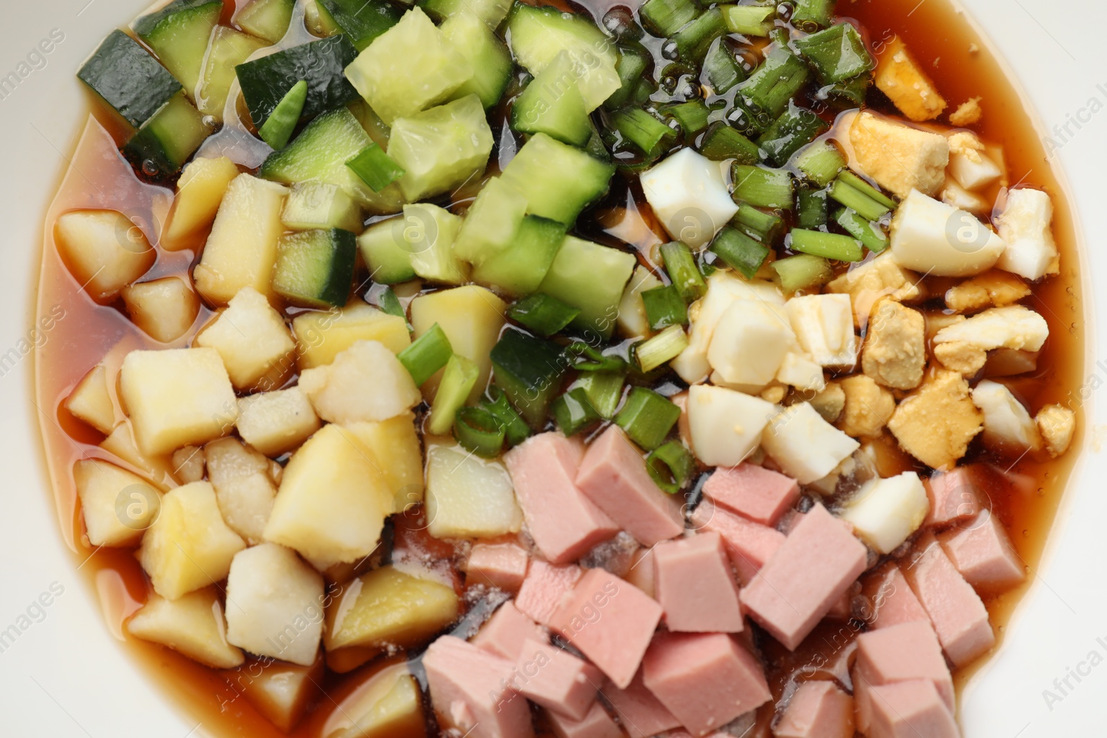 Photo of Tasty okroshka soup with kvass in bowl, top view