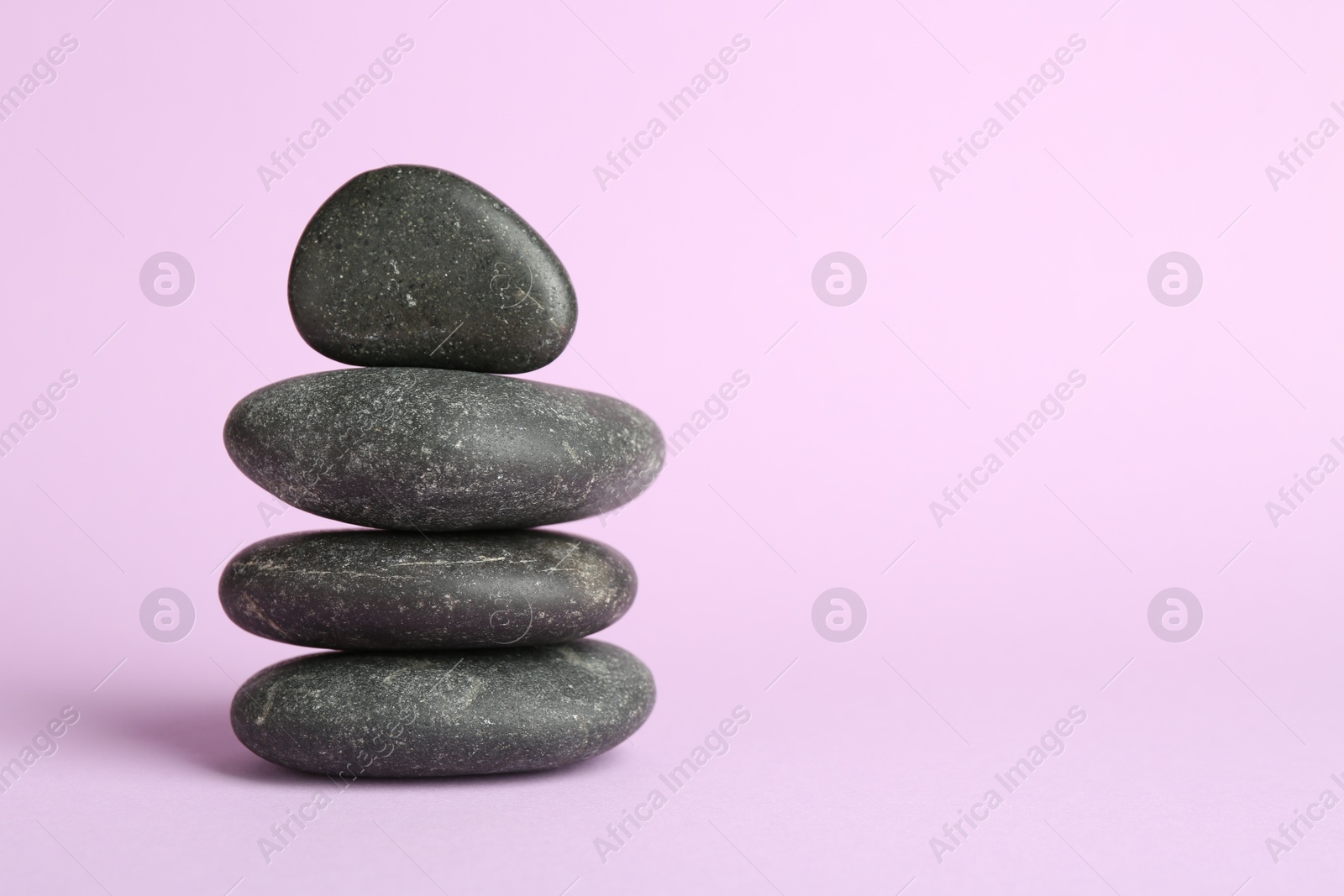 Photo of Stack of rocks on lilac background, space for text. Harmony and life balance