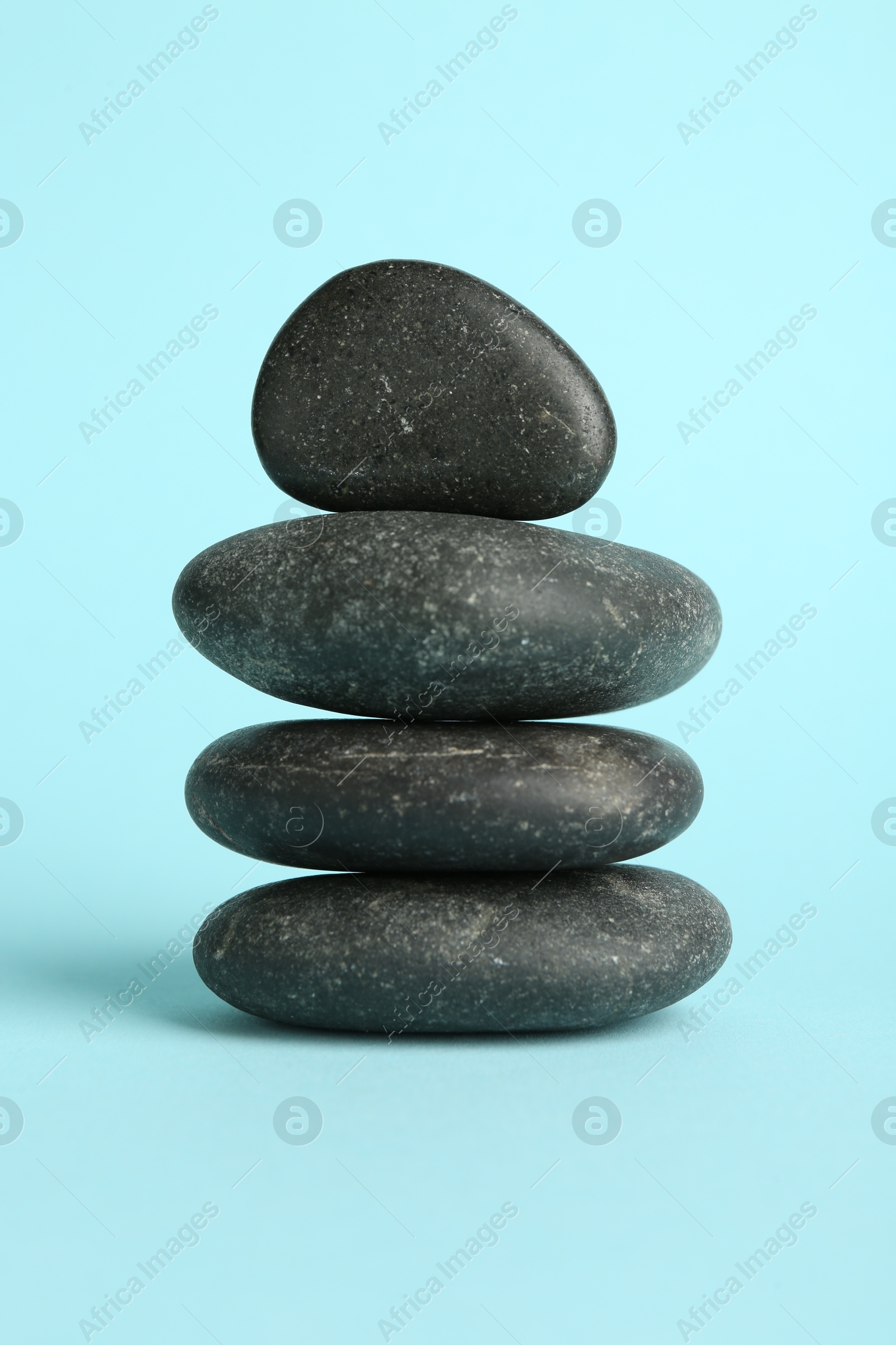 Photo of Stack of rocks on light blue background. Harmony and life balance