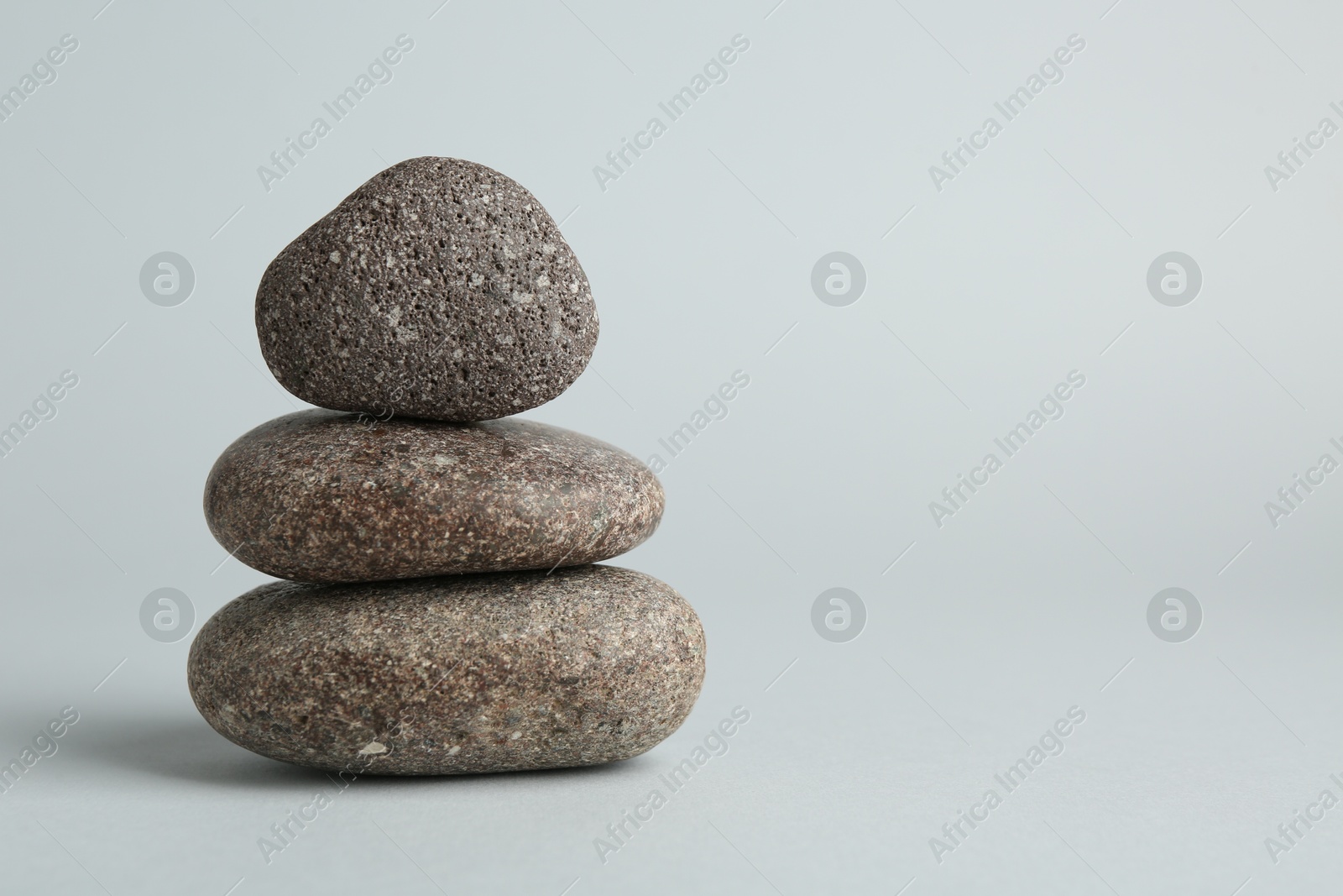 Photo of Stack of rocks on light grey background, space for text. Harmony and life balance