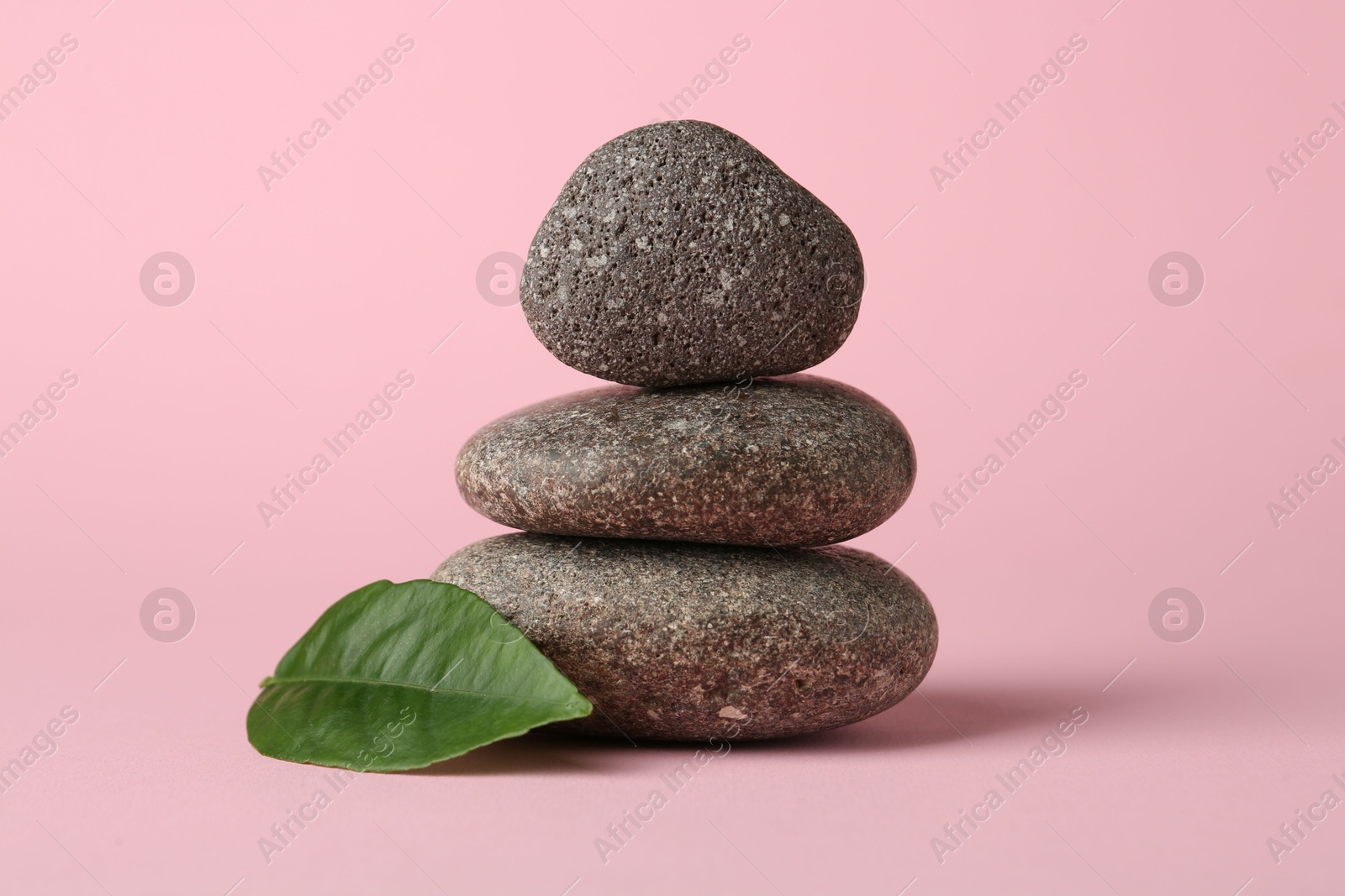 Photo of Stack of rocks on light pink background. Harmony and life balance