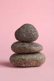 Photo of Stack of rocks on light pink background. Harmony and life balance