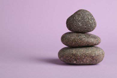 Photo of Stack of rocks on lilac background, space for text. Harmony and life balance