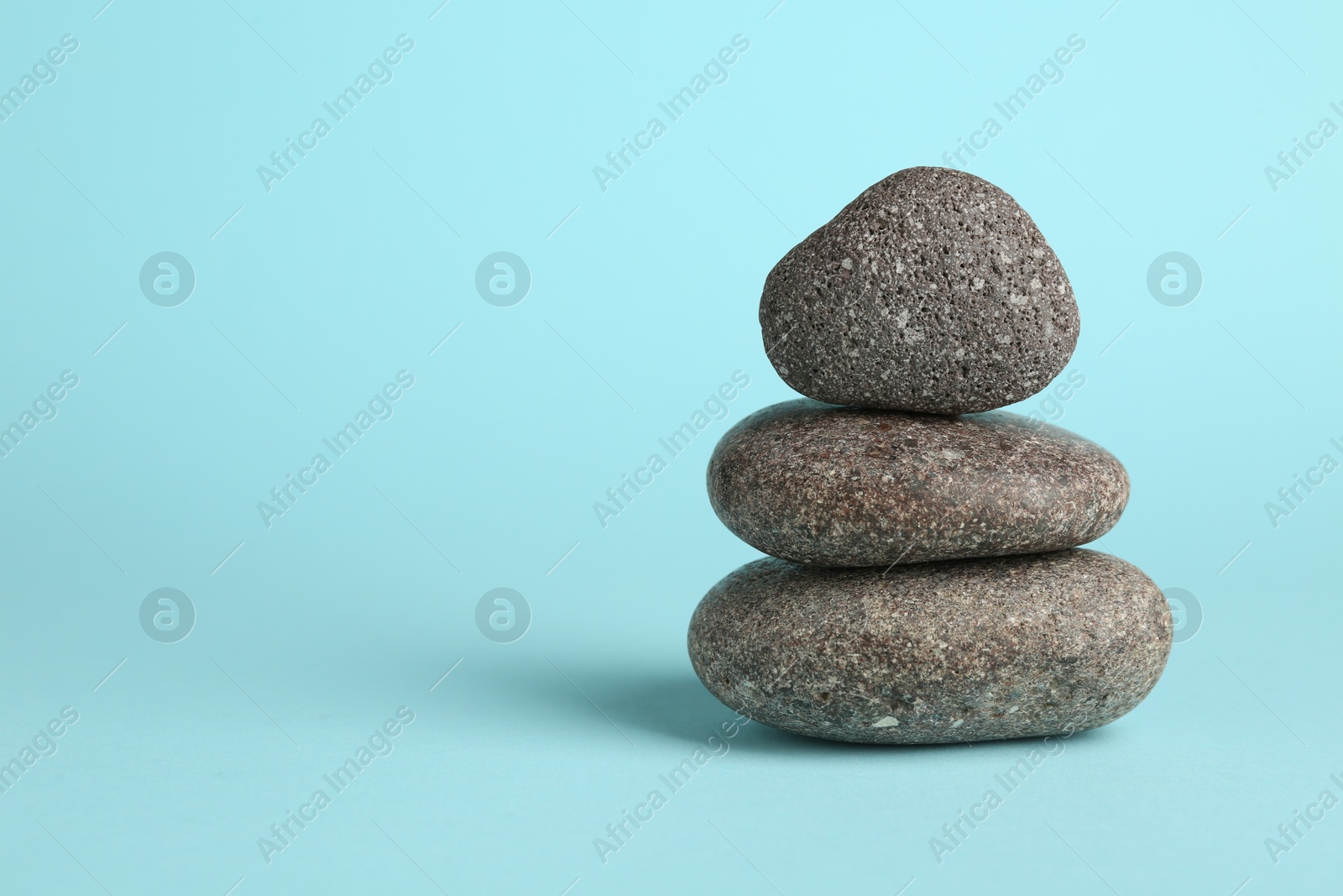 Photo of Stack of rocks on light blue background, space for text. Harmony and life balance