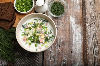 Photo of Delicious okroshka soup in bowl on wooden table, flat lay. Space for text