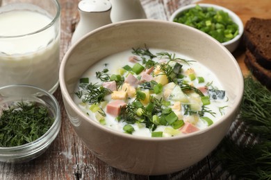 Photo of Delicious okroshka soup in bowl on wooden table, closeup