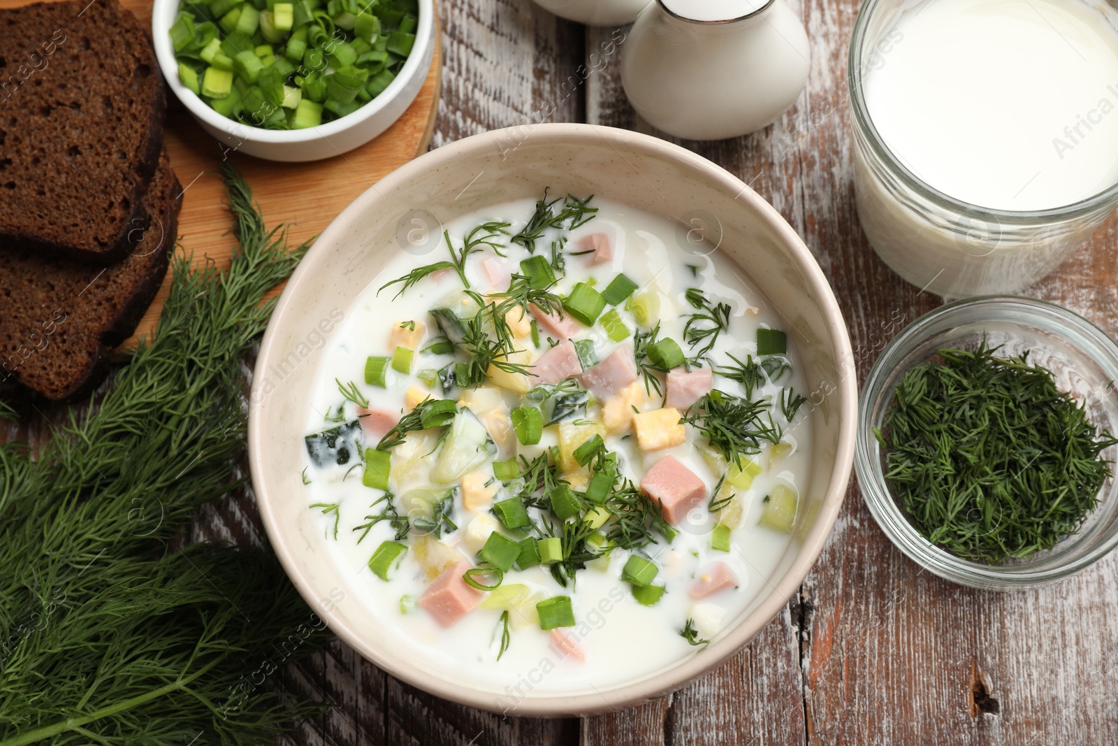 Photo of Delicious okroshka soup in bowl on wooden table, flat lay