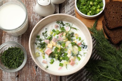 Photo of Delicious okroshka soup in bowl on wooden table, flat lay