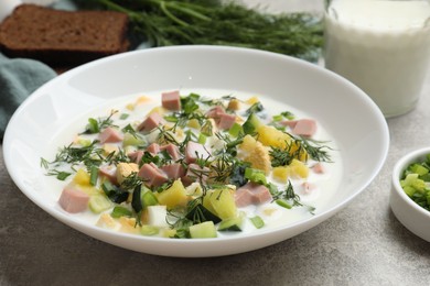 Photo of Delicious okroshka soup in bowl on grey textured table, closeup