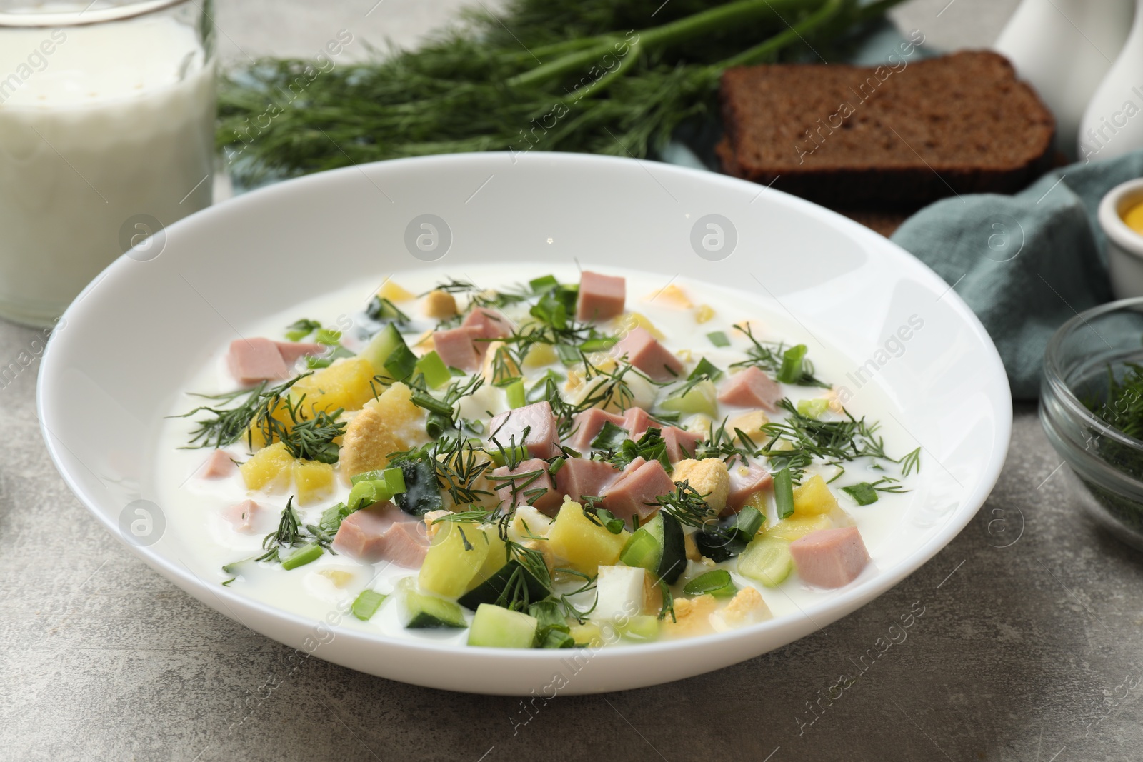 Photo of Delicious okroshka soup in bowl on grey textured table, closeup