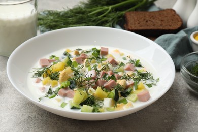 Photo of Delicious okroshka soup in bowl on grey textured table, closeup