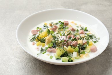 Photo of Delicious okroshka soup in bowl on grey textured table, closeup