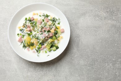 Photo of Delicious okroshka soup in bowl on grey textured table, top view. Space for text