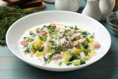 Photo of Delicious okroshka soup in bowl on light blue wooden table, closeup