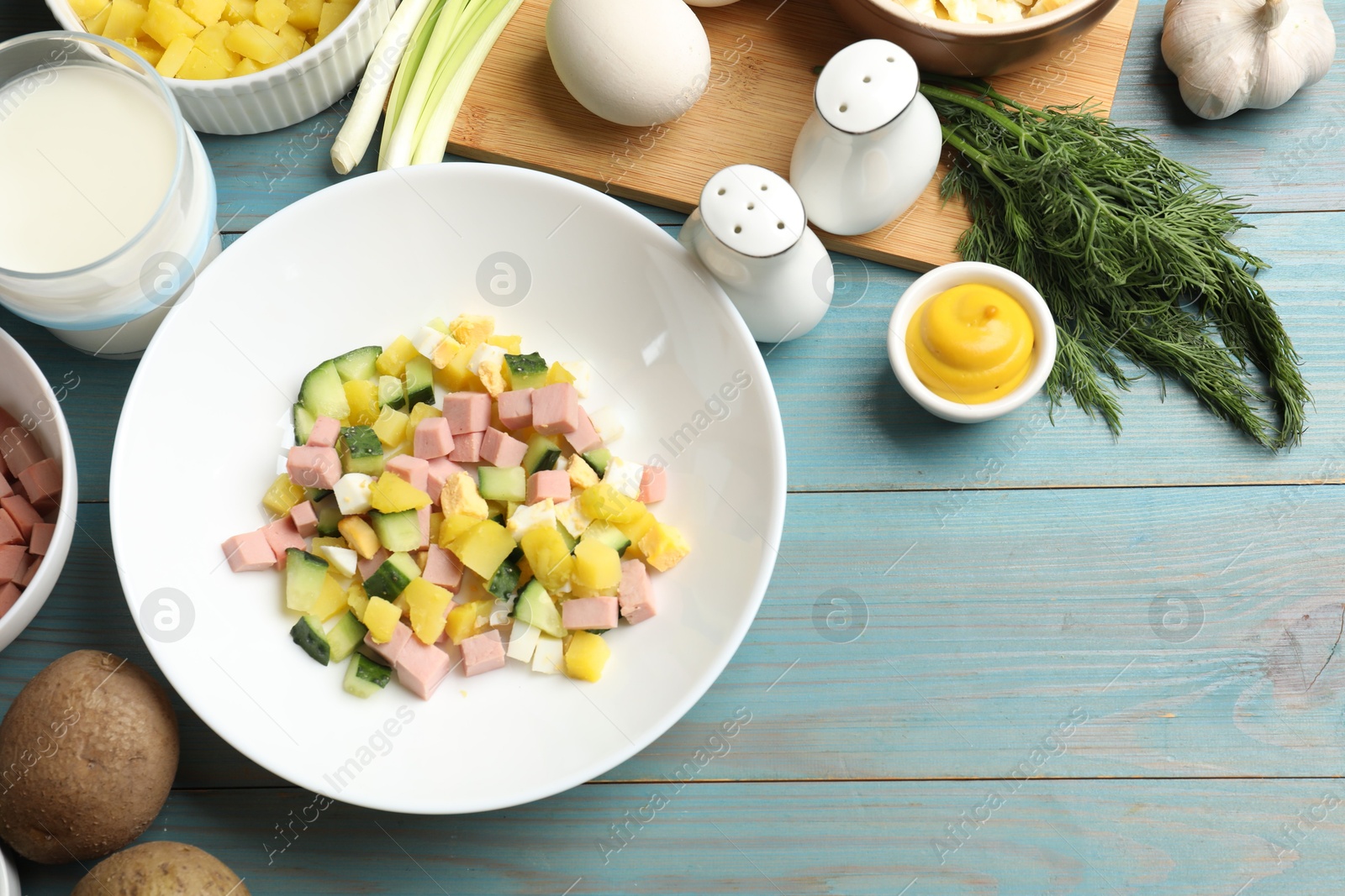 Photo of Ingredients for okroshka soup on light blue wooden table, flat lay. Space for text