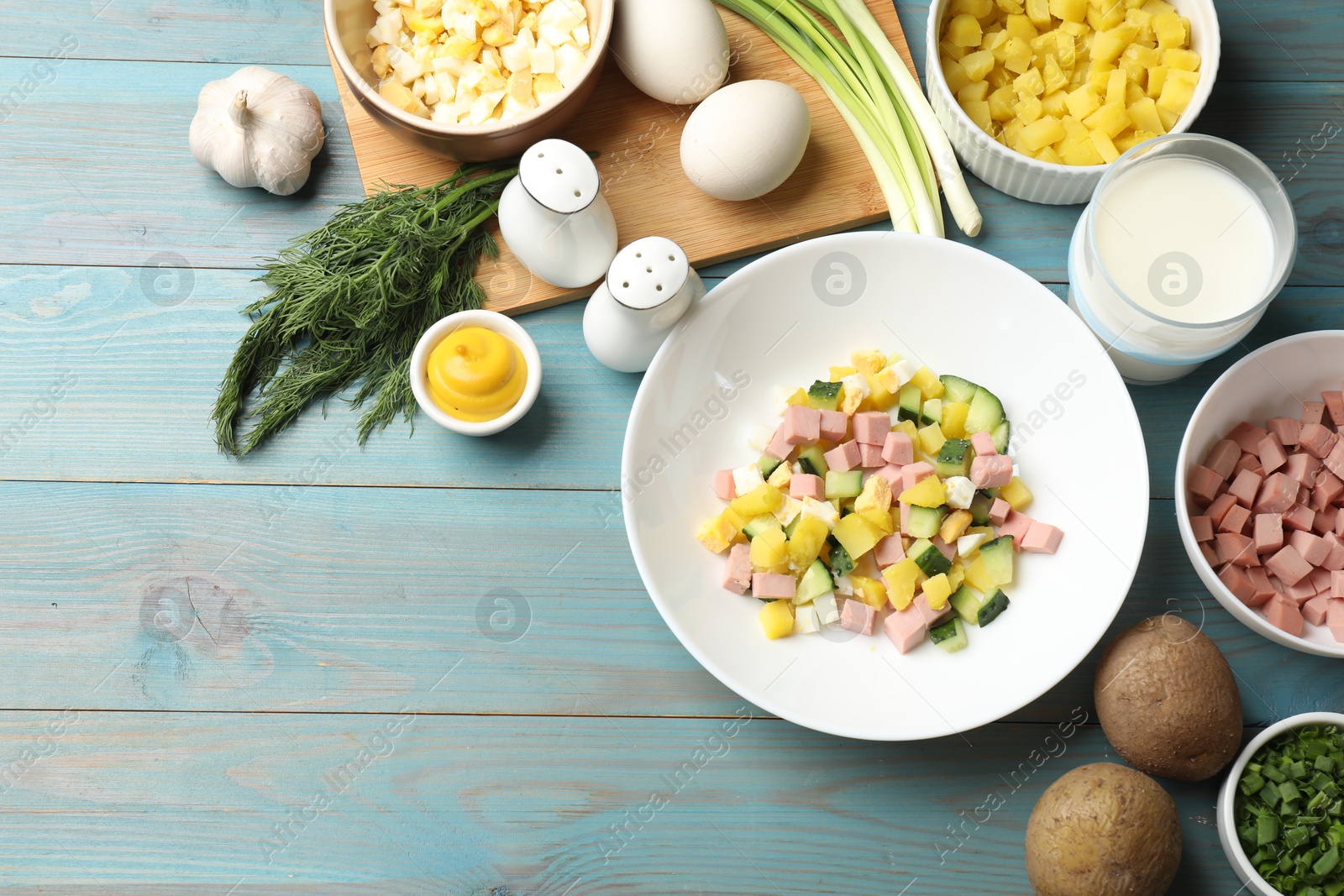 Photo of Ingredients for okroshka soup on light blue wooden table, flat lay. Space for text