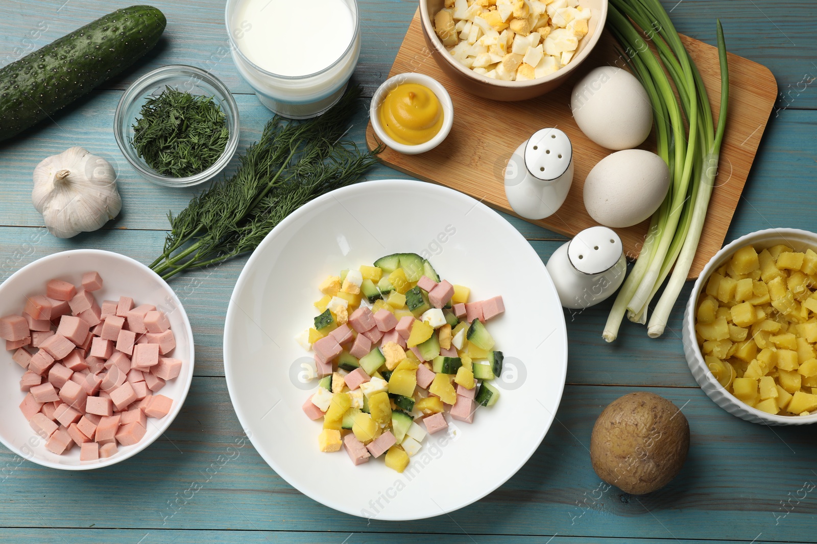 Photo of Ingredients for okroshka soup on light blue wooden table, flat lay