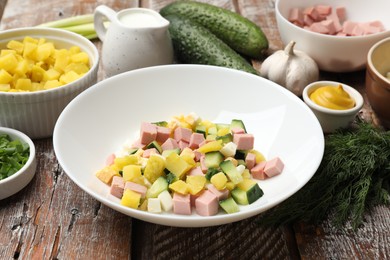 Photo of Ingredients for okroshka soup in bowl on wooden table, closeup