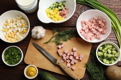 Photo of Cut ingredients for okroshka soup and knife on wooden table, flat lay