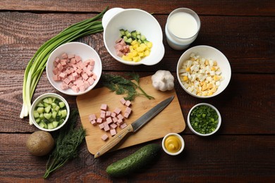 Photo of Cut ingredients for okroshka soup and knife on wooden table, flat lay