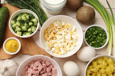 Photo of Fresh ingredients for okroshka soup on light wooden table, flat lay