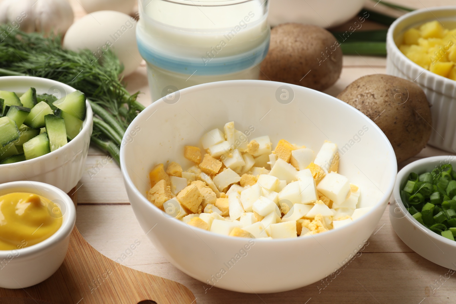 Photo of Fresh ingredients for okroshka soup on light wooden table, closeup