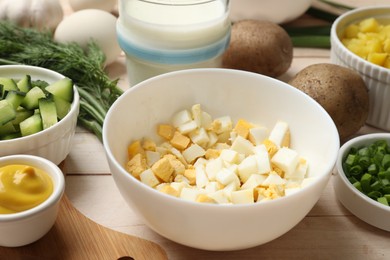 Photo of Fresh ingredients for okroshka soup on light wooden table, closeup