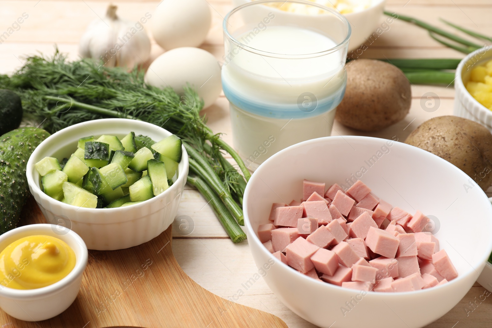 Photo of Fresh ingredients for okroshka soup on light wooden table, closeup