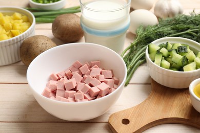 Photo of Fresh ingredients for okroshka soup on light wooden table, closeup