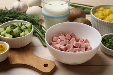 Photo of Fresh ingredients for okroshka soup on light wooden table, closeup