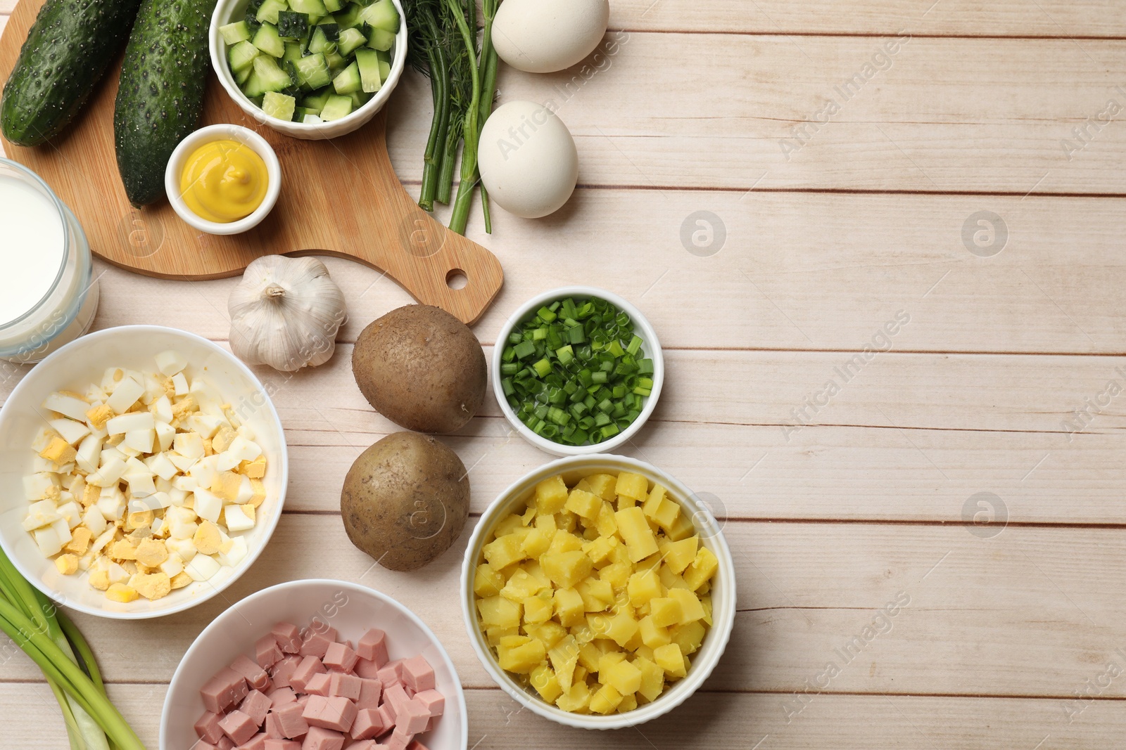 Photo of Ingredients for okroshka soup on light wooden table, flat lay. Space for text