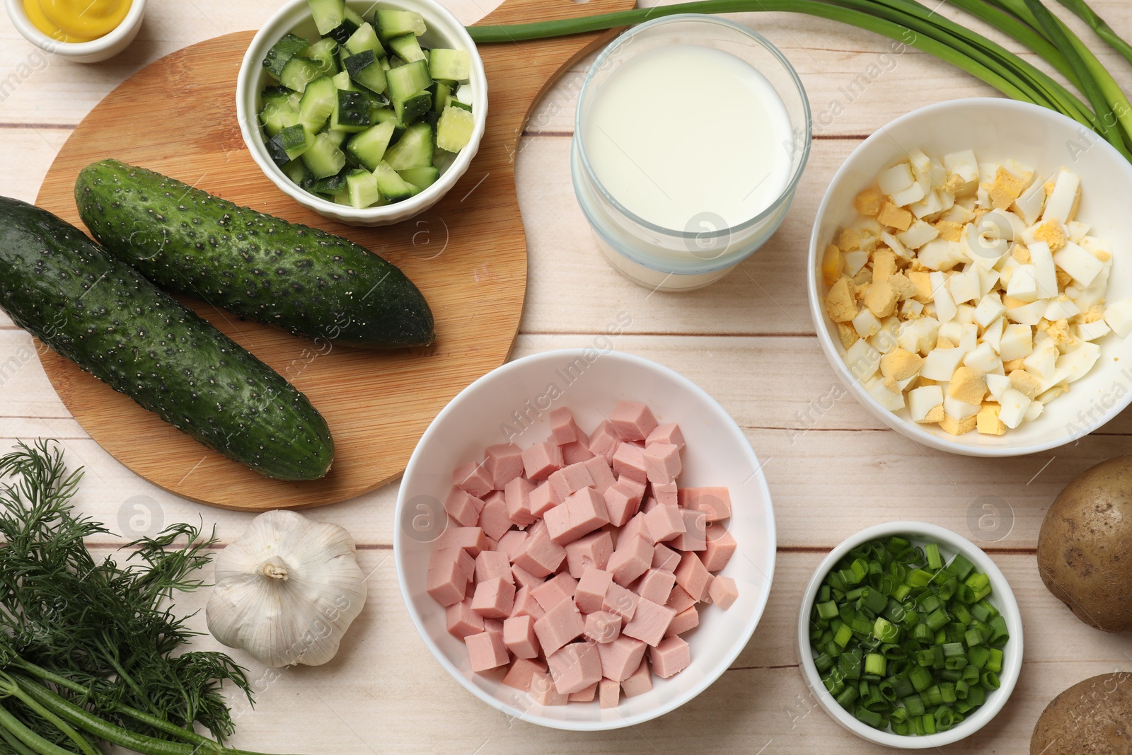 Photo of Fresh ingredients for okroshka soup on light wooden table, flat lay