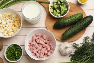 Photo of Fresh ingredients for okroshka soup on light wooden table, flat lay