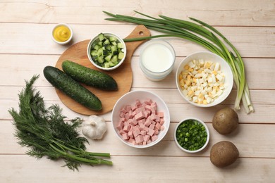 Photo of Fresh ingredients for okroshka soup on light wooden table, flat lay