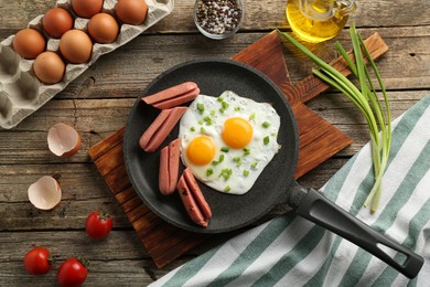 Photo of Tasty fried eggs with cut sausages served on wooden table, flat lay