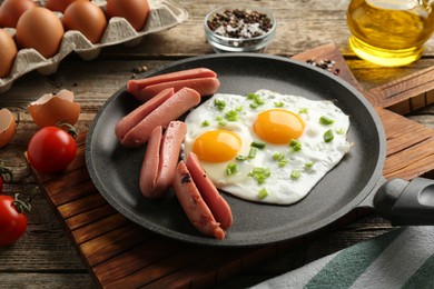 Photo of Tasty fried eggs with cut sausages served on wooden table, closeup