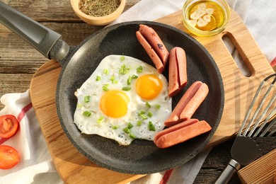 Photo of Tasty fried eggs with cut sausages served on wooden table, flat lay