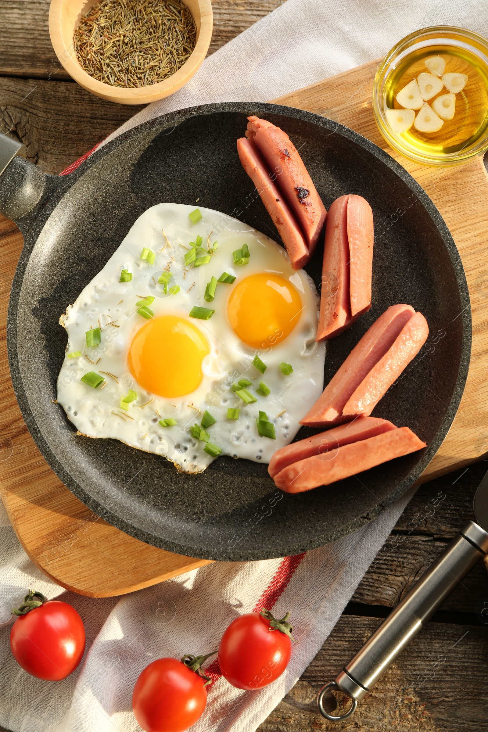 Photo of Tasty fried eggs with cut sausages served on wooden table, flat lay