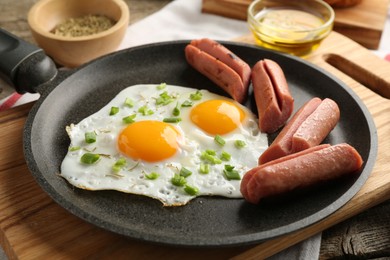 Photo of Tasty fried eggs with cut sausages served on table, closeup